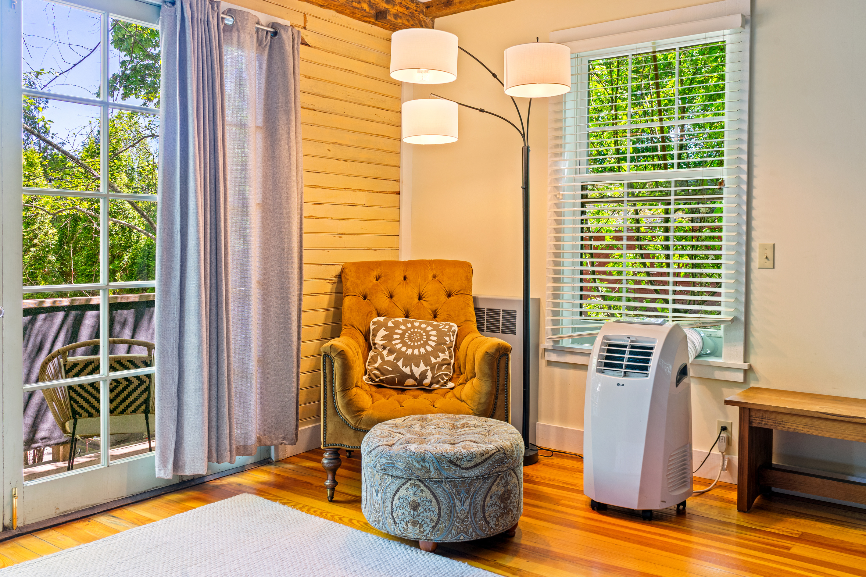 A private plotting nook inside the Captain's quarters. This corner features an armchair and ottoman set beneath multi-directional lighting, complete with a dedicated AC unit and French doors opening out to the fresh air of the private bridge balcony.