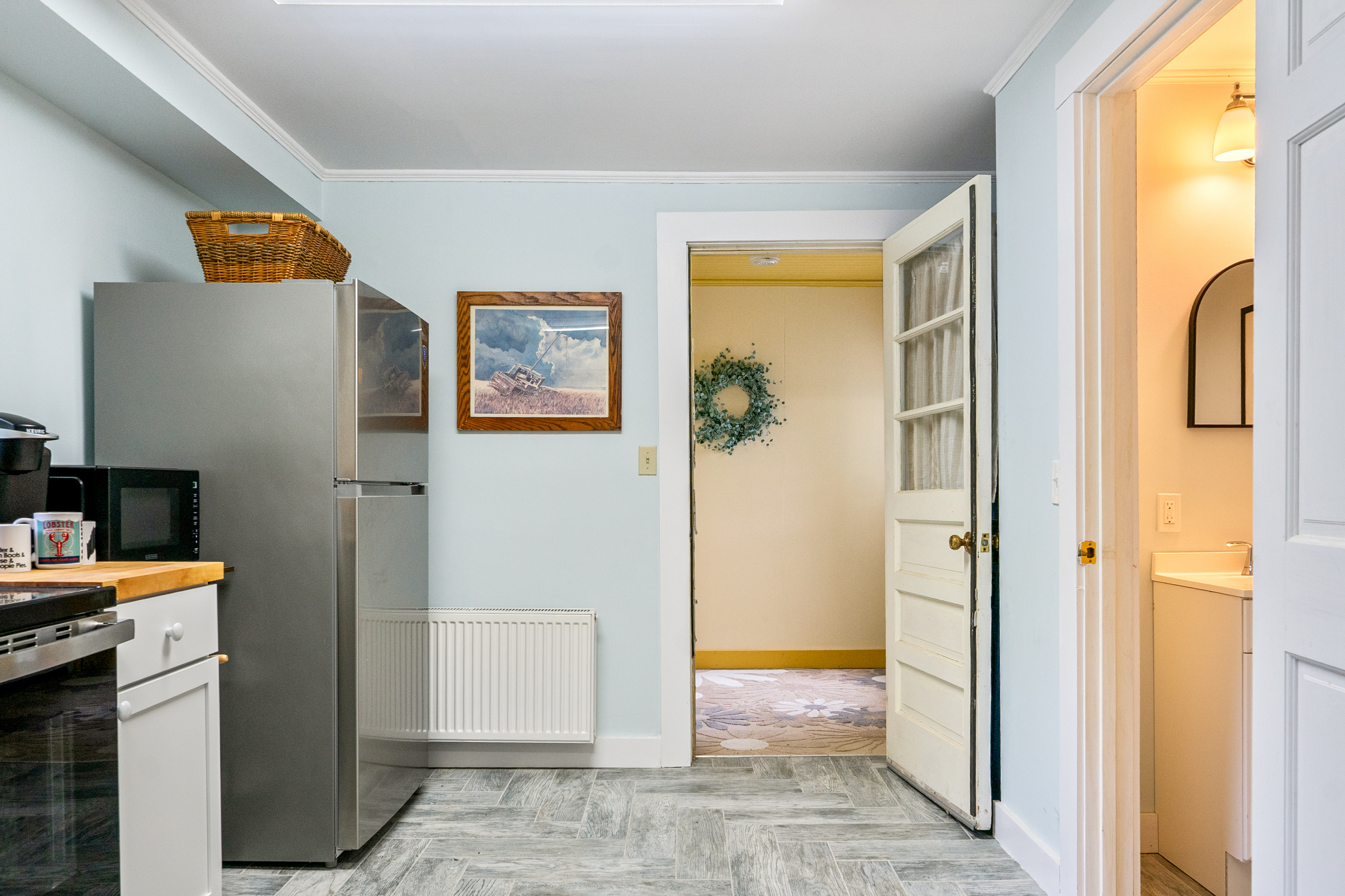 Step inside from the side door straight into the core layout. This view shows how the mudroom connects directly to the kitchen, complete with a full-size stainless steel refrigerator and an easily accessible first-floor half bath for your group.