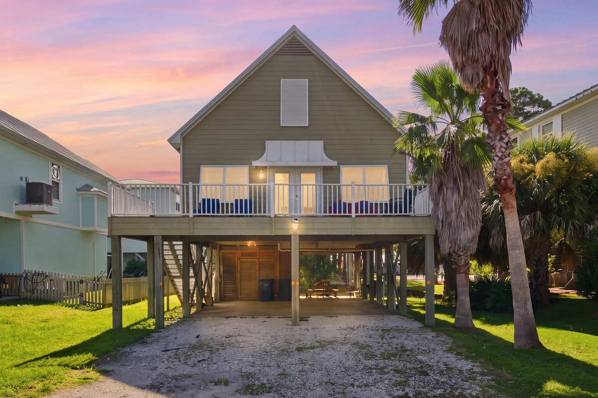 This raised coastal cottage welcomes you to Bear Point, with covered parking underneath and swaying palms setting the tone for your Orange Beach getaway.