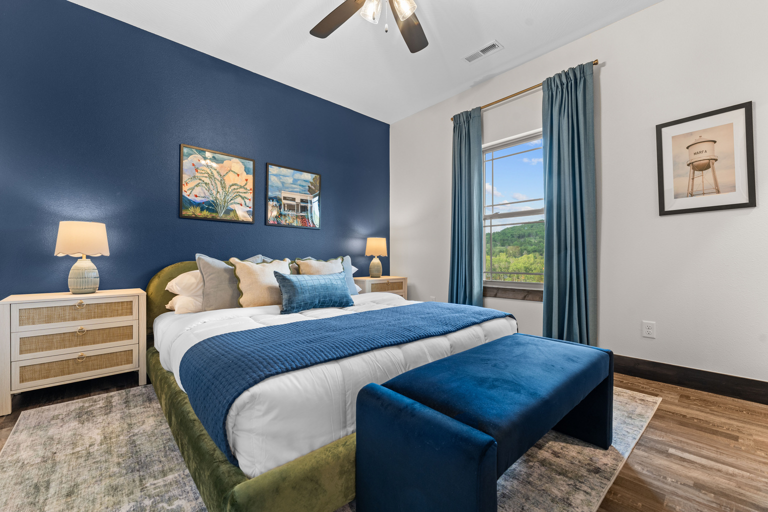 Drift off in the Marfa Room, a king bedroom with desert art and a Texas water-tower print over a moody navy wall.