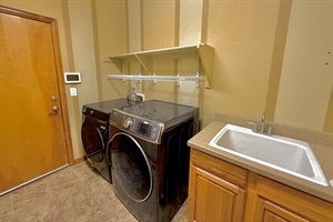 Convenient laundry room equipped with a washer, dryer, and sink for all your cleaning needs, located at the main level