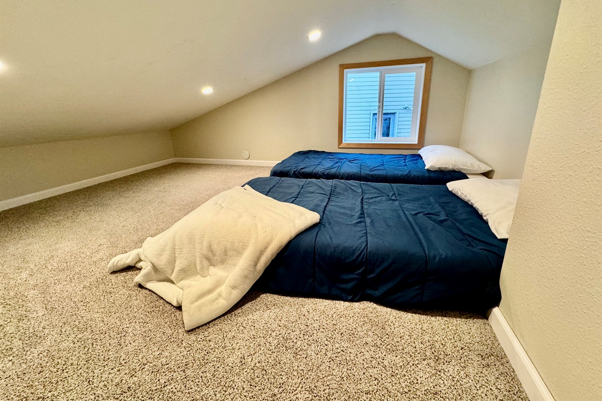 2 twin beds at top of spiral staircase in loft