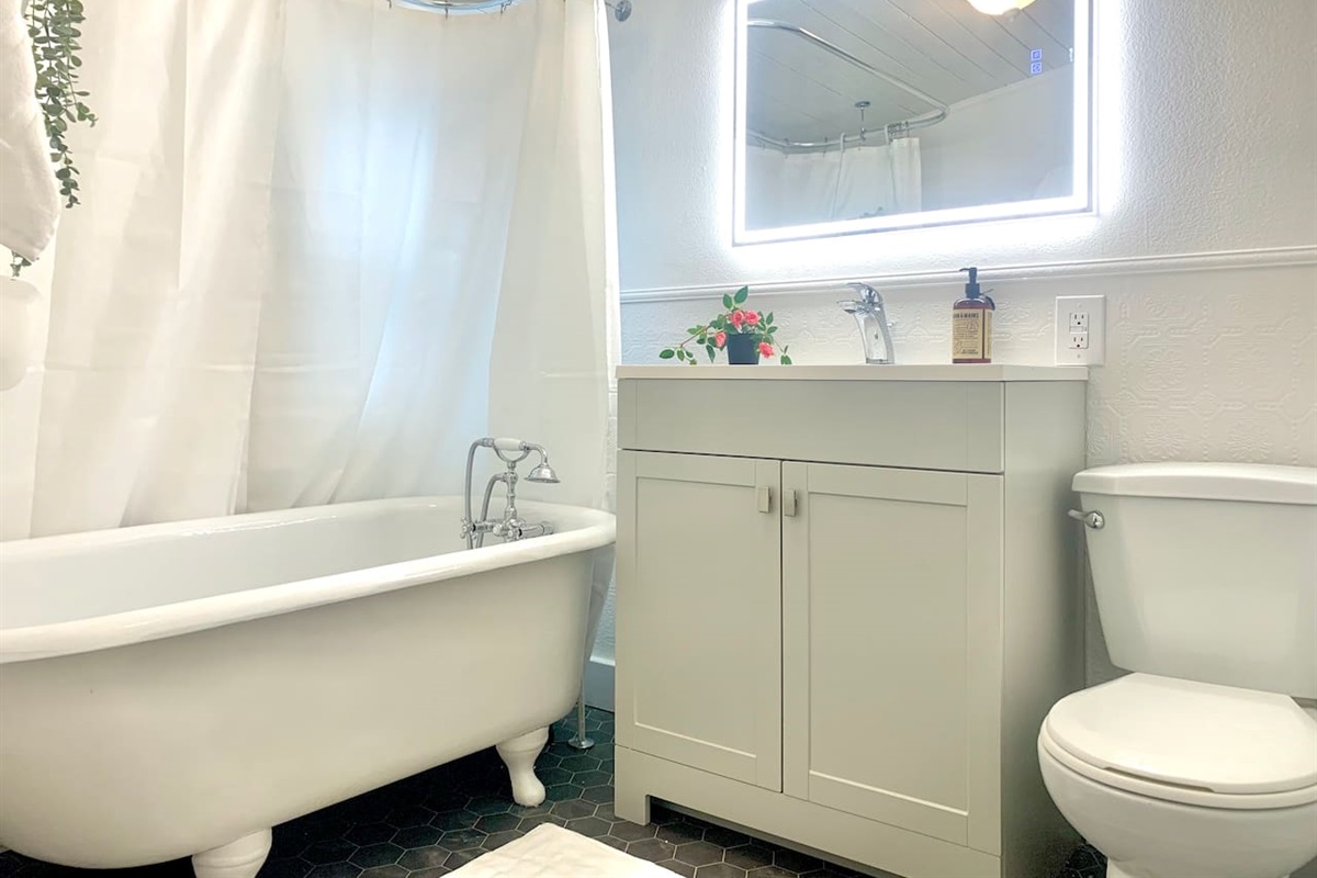 Full bathroom with the original refinished clawfoot soaker tub, hand held shower nozzle, vanity, and fresh towels provided. 