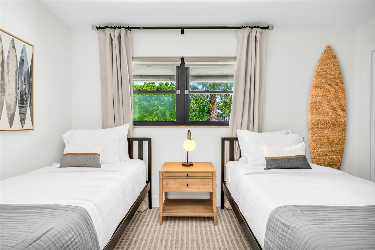 This light-filled twin bedroom combines comfort and style with coastal surf accents, two cozy twin beds, and premium linens. Guests will love the ROKU TV for entertainment and the abundant sto