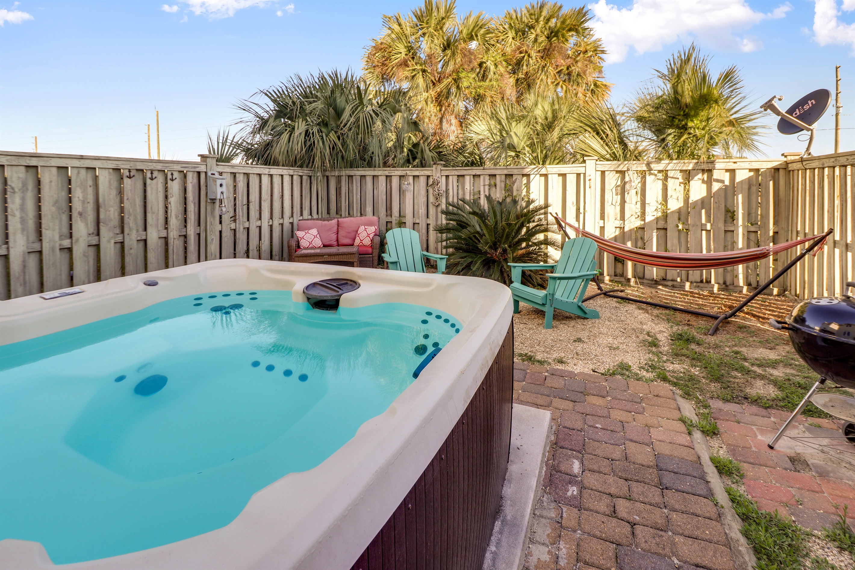 private backyard with hot tub, hammock, fire pit, and grill