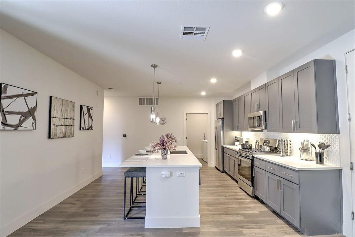 - Experience an open kitchen with modern gray cabinetry and polished counters   - Designed for convenience with stainless steel appliances and bar seating   - Ideal for cooking, chatting, and creating memorable dining moments together