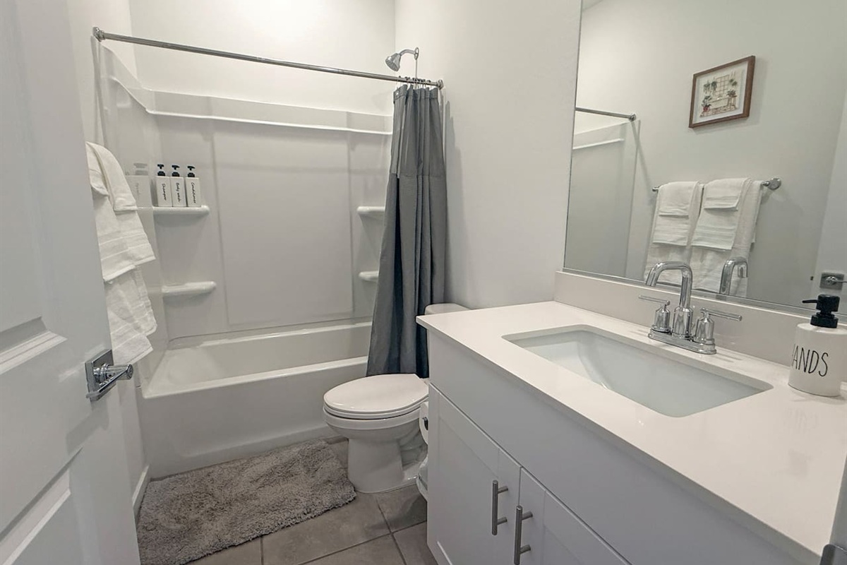 Bathroom with tub-shower, toilet, vanity, and towels