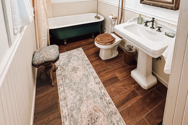 Slip into the deep clawfoot tub in the primary suite’s private bath, where a pedestal sink, pull chain commode and a stained glass window continue the home’s historic character. The dressing room creates a graceful buffer from the bedroom.