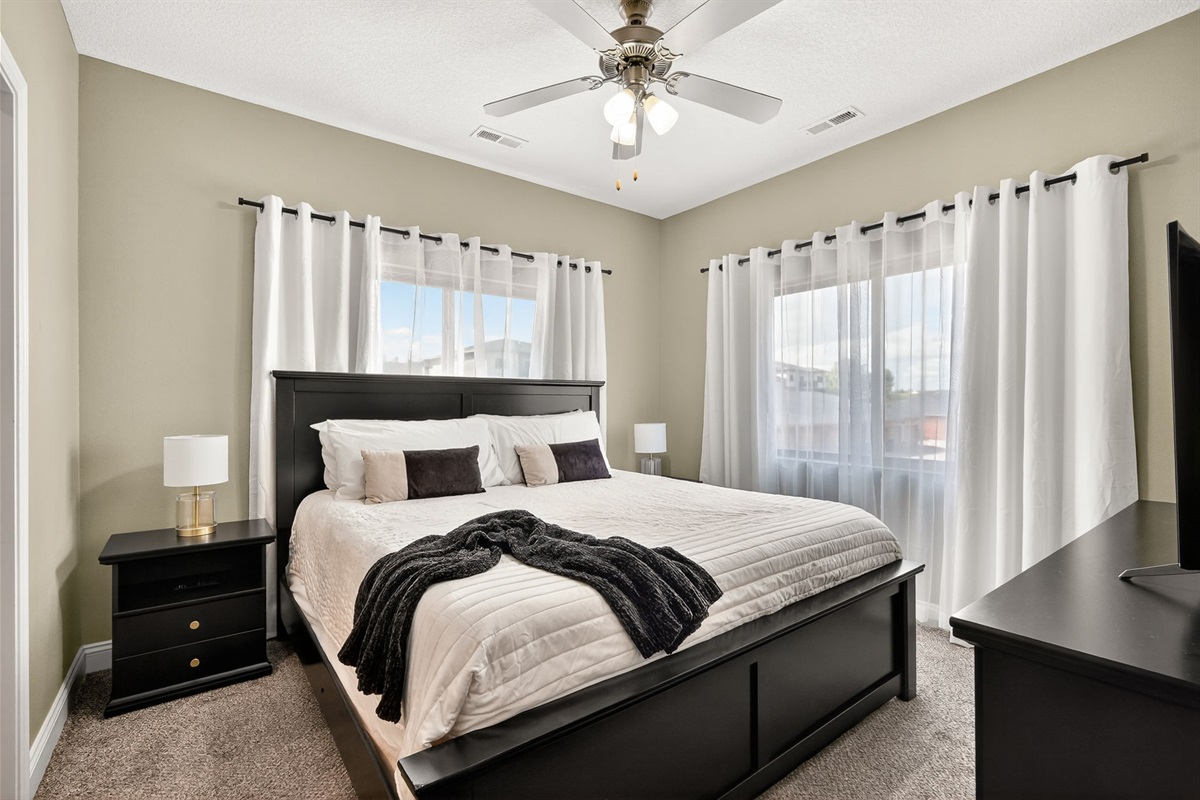 Corner unit = tons of light!  The primary bedroom with king sized bed and room darkening curtains.