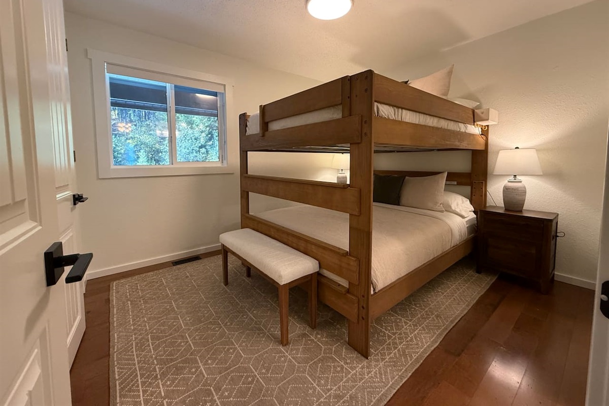 The main floor bedroom features a unique adult bunk bed with a queen-size mattress on both the top and bottom bunks, comfortably sleeping four adults. This layout is designed to maximize space without sacrificing comfort.