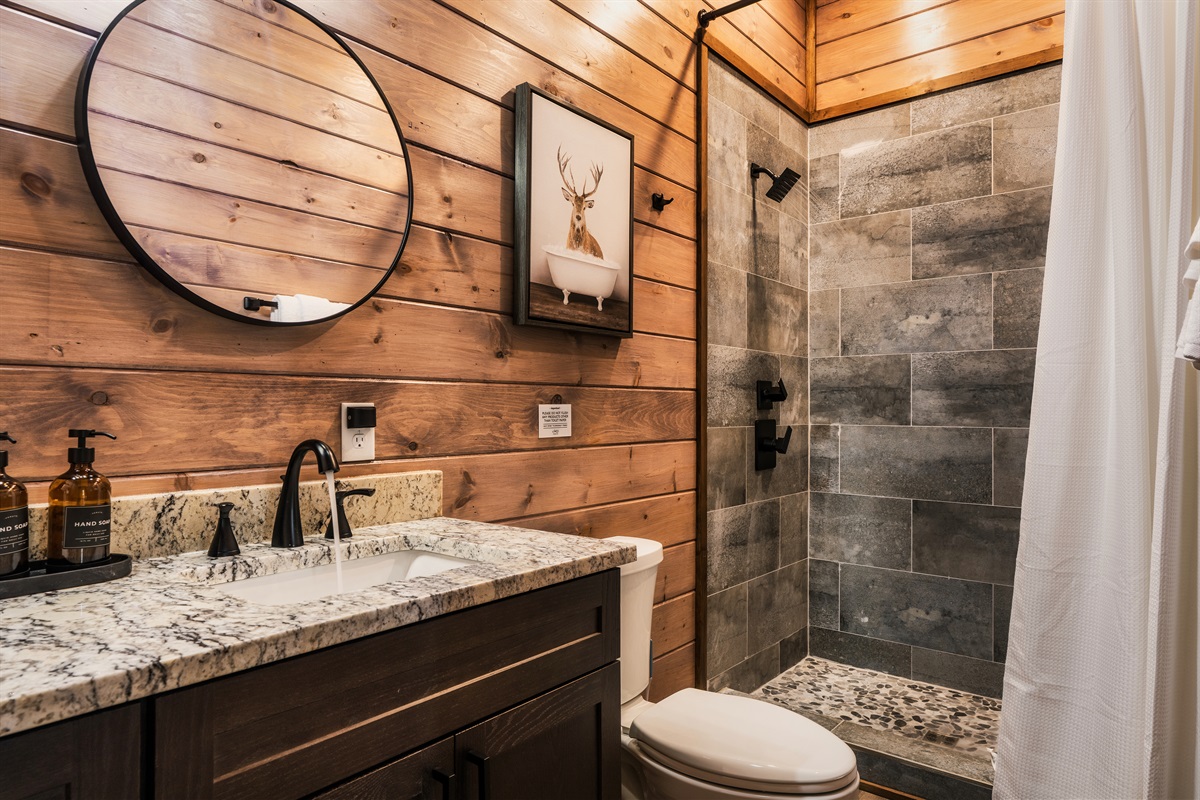 Full bathroom with round mirror, shelf space, and tasteful decor.