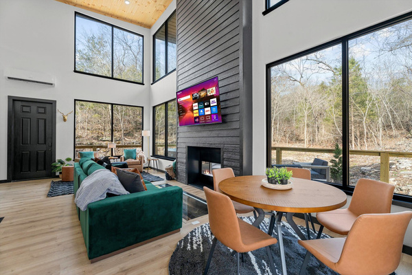 Experience the soaring, sunlit living area with large windows, plush seating, and a stylish indoor-outdoor fireplace!