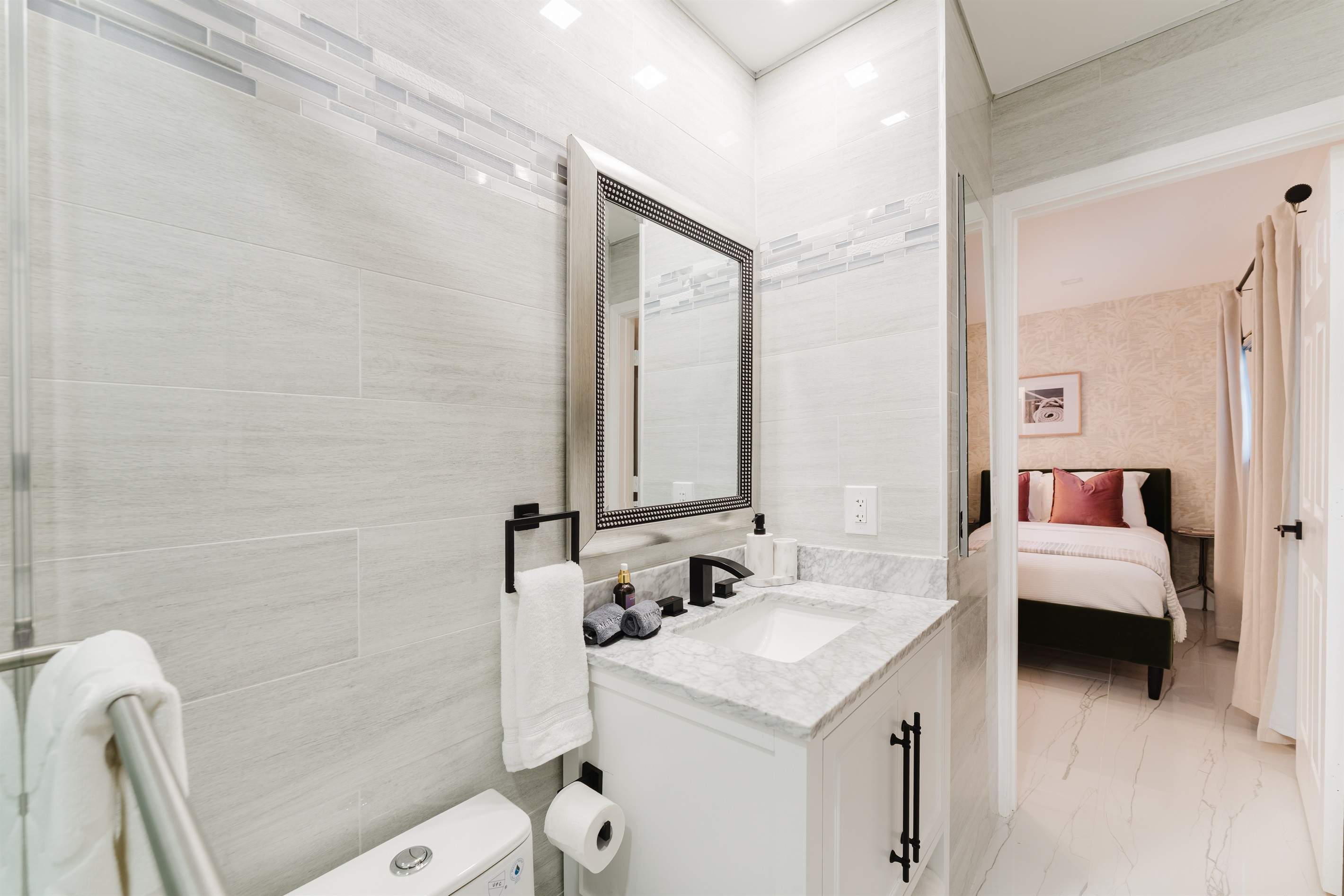 Private spa-style ensuite with a glass-enclosed walk-in shower, marble vanity, matte black fixtures, and hotel-quality finishes.