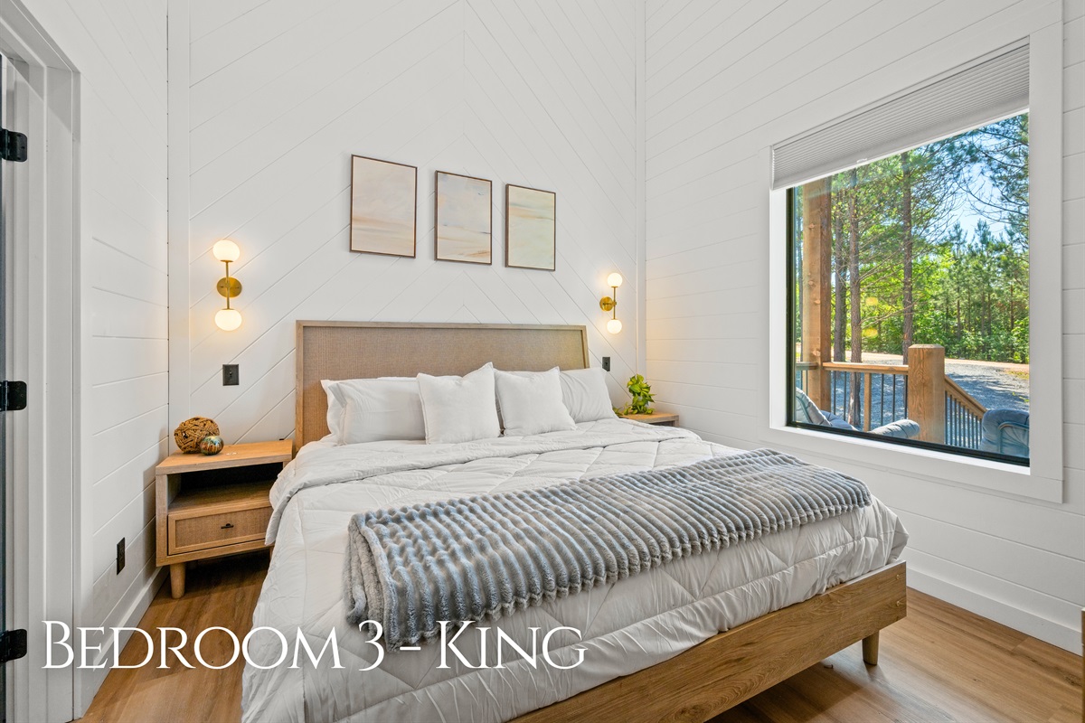 Soft neutral tones, natural light, and peaceful wooded views help this king bedroom feel bright, cozy, and ideal for restful mornings and quiet evenings.