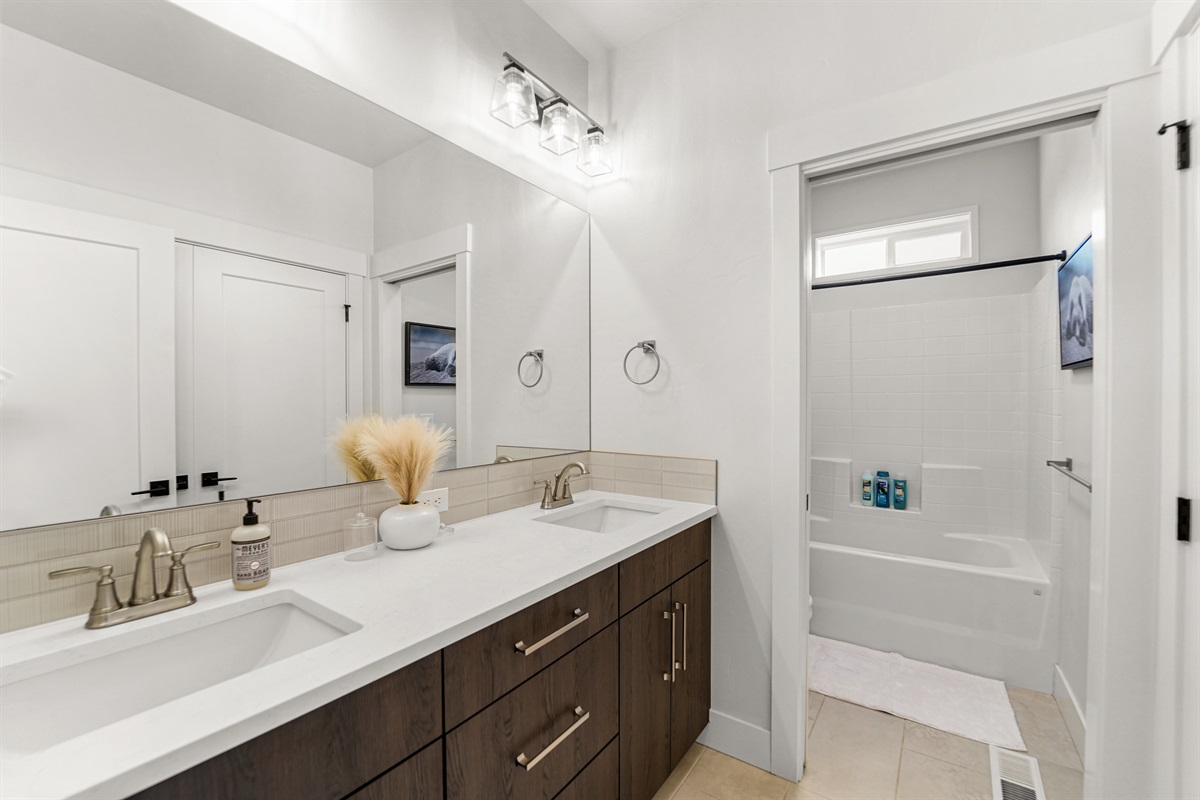 Modern bathroom featuring dual sinks and a convenient shower/tub