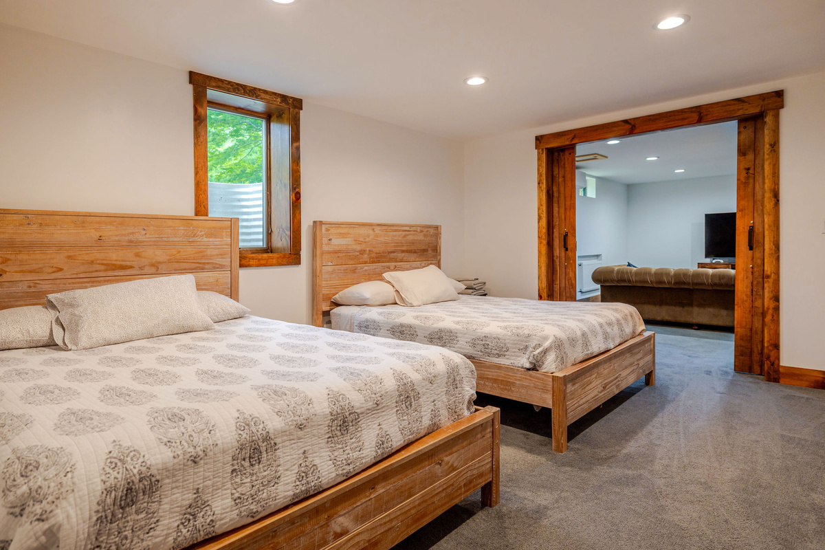 Bedroom 5 features two comfortable queen beds, making it an ideal space for families or friends. Conveniently located next to the lower-level family room, it's perfect for larger groups traveling together.