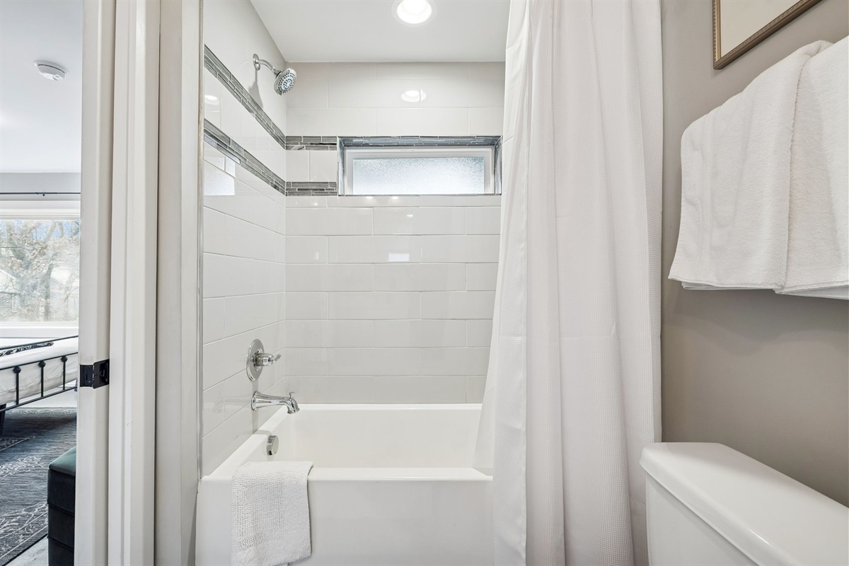 - Clean lines and bright white tile give this bathroom a modern, refreshing feel - Round mirror, open shelving, and thoughtful touches make it both stylish and functional - Perfect for freshening up after a day out or unwinding with a relaxing soak