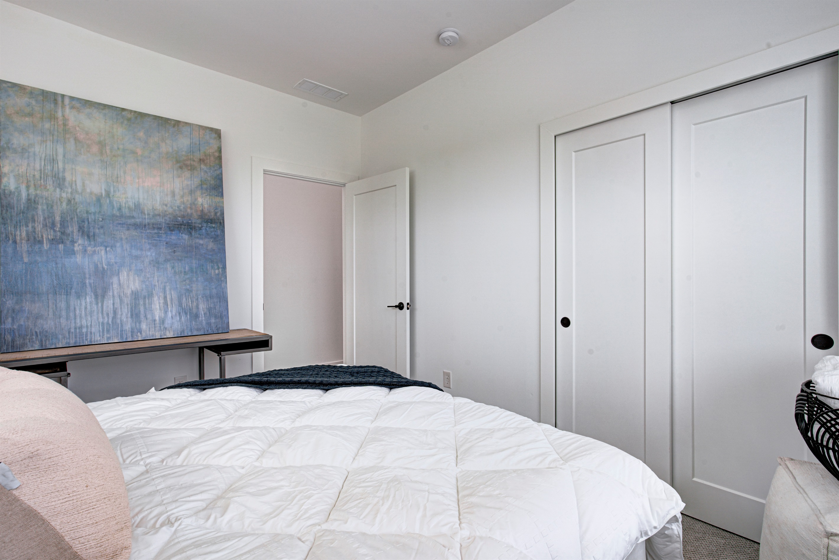Relax in the serene master bedroom featuring a comfortable king-size bed, soft linens, and cozy pillows. Includes nightstands, lamps, walk-in closet, and full-length mirror for added comfort. 