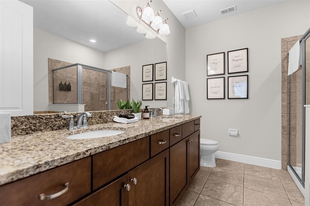 Modern bathroom equipped with a generous vanity area, a toilet, and a walk-in shower, offering a stylish and functional space for relaxation and refreshment.