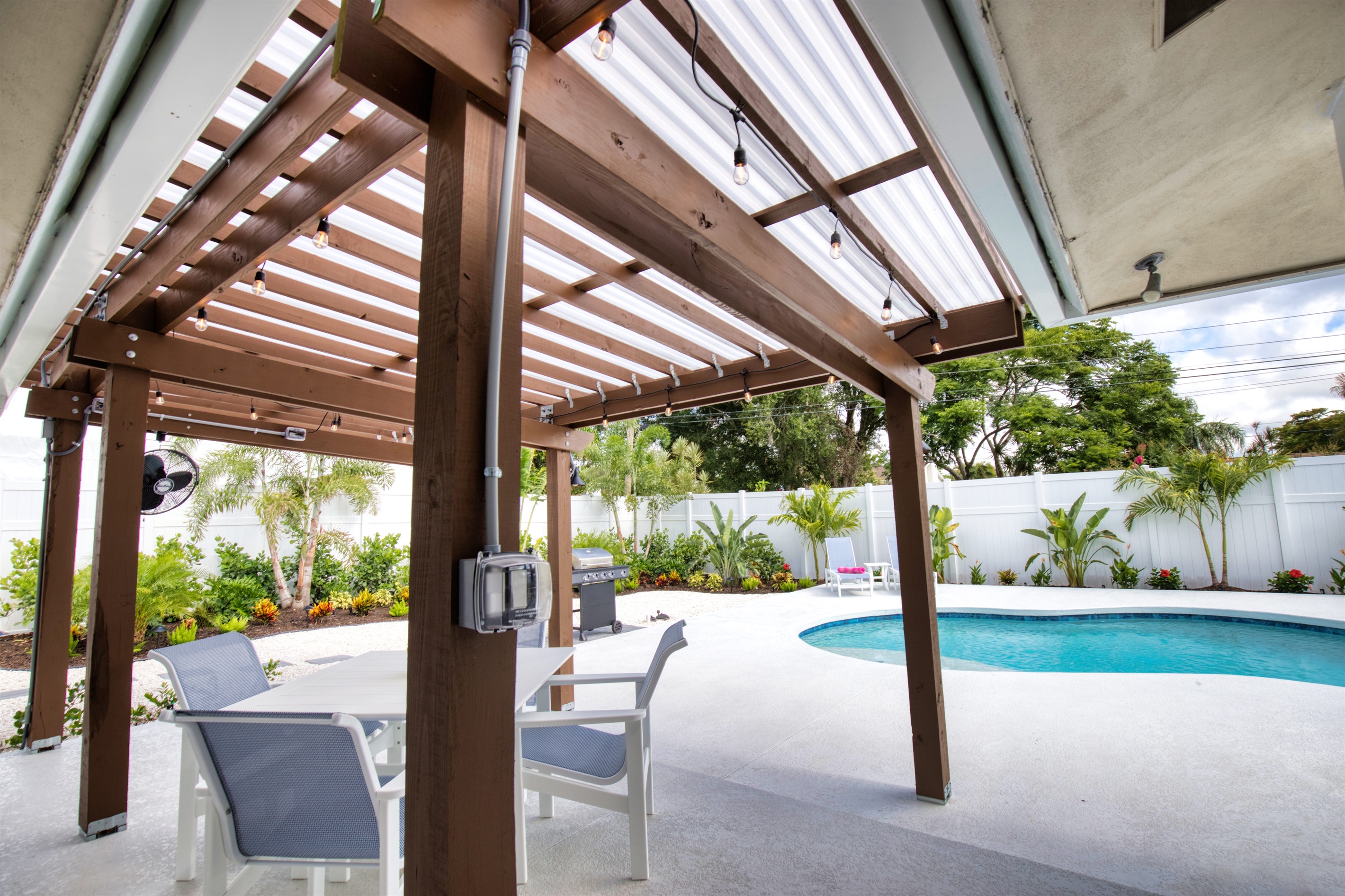Patio area with covered pergola, dining table with four chairs, 65" TV and fan to keep you cool.