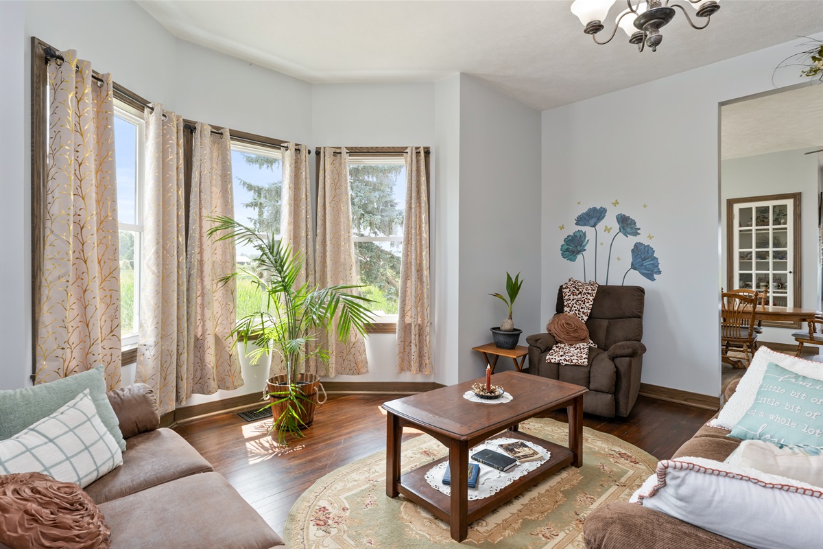 Bright and inviting living room with bay windows, cozy seating, and natural light—perfect for relaxing with a view.