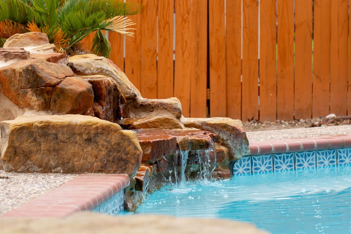 The unique waterfall adds character to the swimming pool.