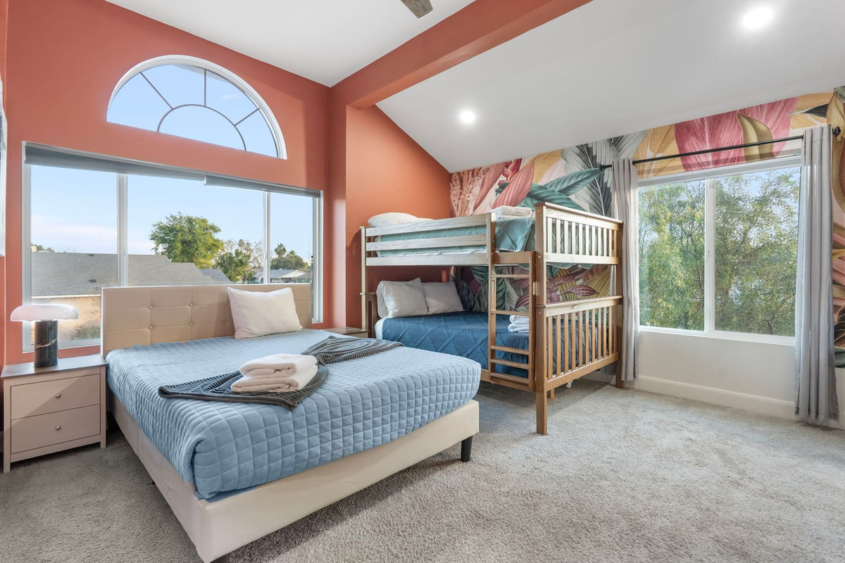 Bright, cheerful kids' bedroom with queen bed, bunk beds, and plenty of natural light for family groups.