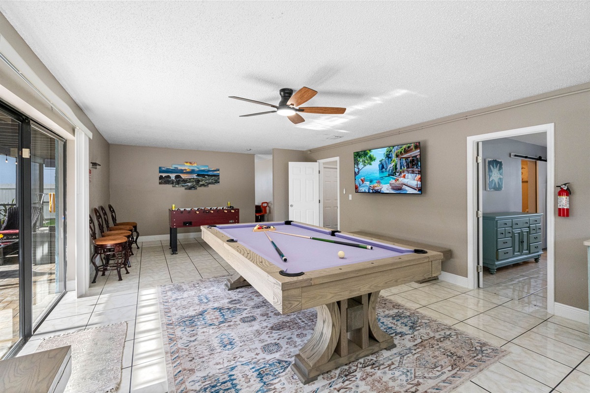 The room is thoughtfully designed with soft neutral tones, tile flooring for easy cleanup, and a ceiling fan to keep you cool while the action heats up.