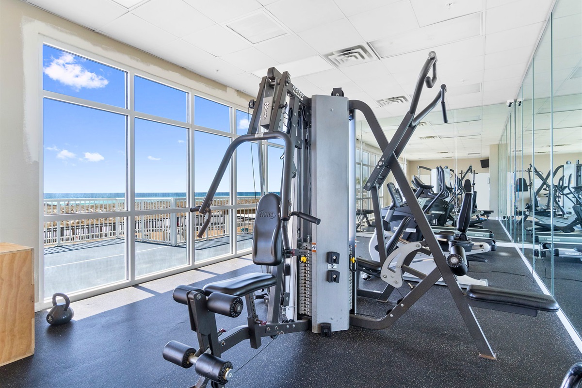 Large windows fill the fitness center with natural light while providing inspiring views of the beach beyond.