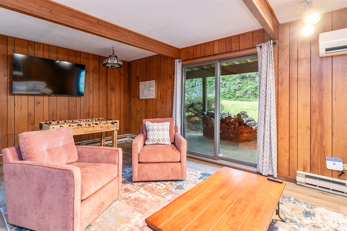 Fun-filled family room featuring foosball, plush seating, and sliding doors that open to the outdoors—ideal for game nights and relaxation.