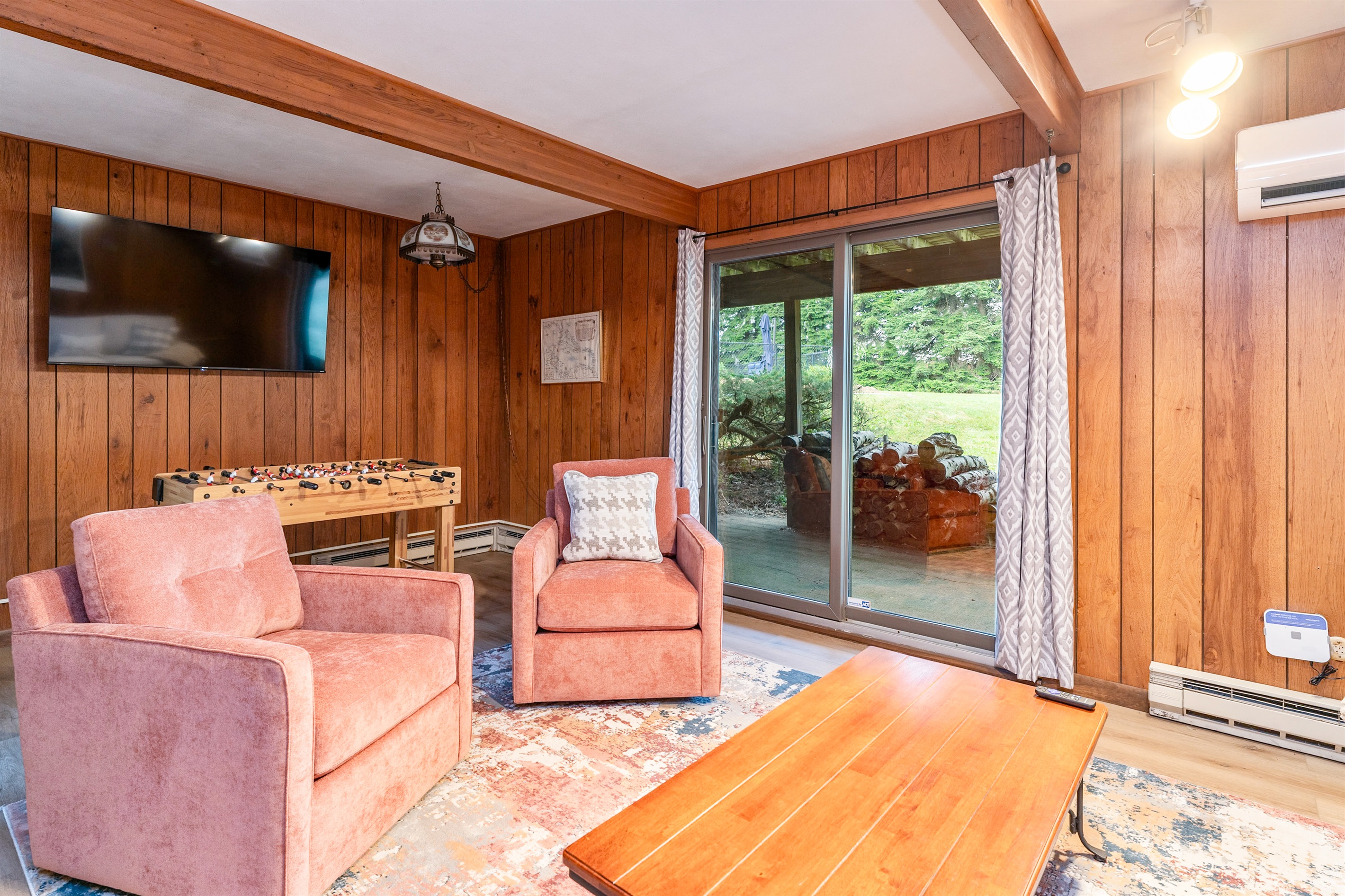 Fun-filled family room featuring foosball, plush seating, and sliding doors that open to the outdoors—ideal for game nights and relaxation.
