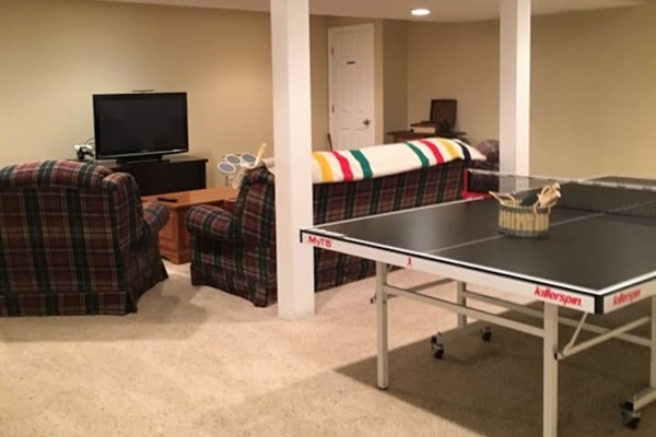 Basement with ping pong table and couches.