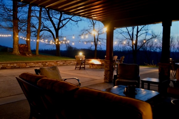 Relax under the covered patio with views of the fire pit and string lights