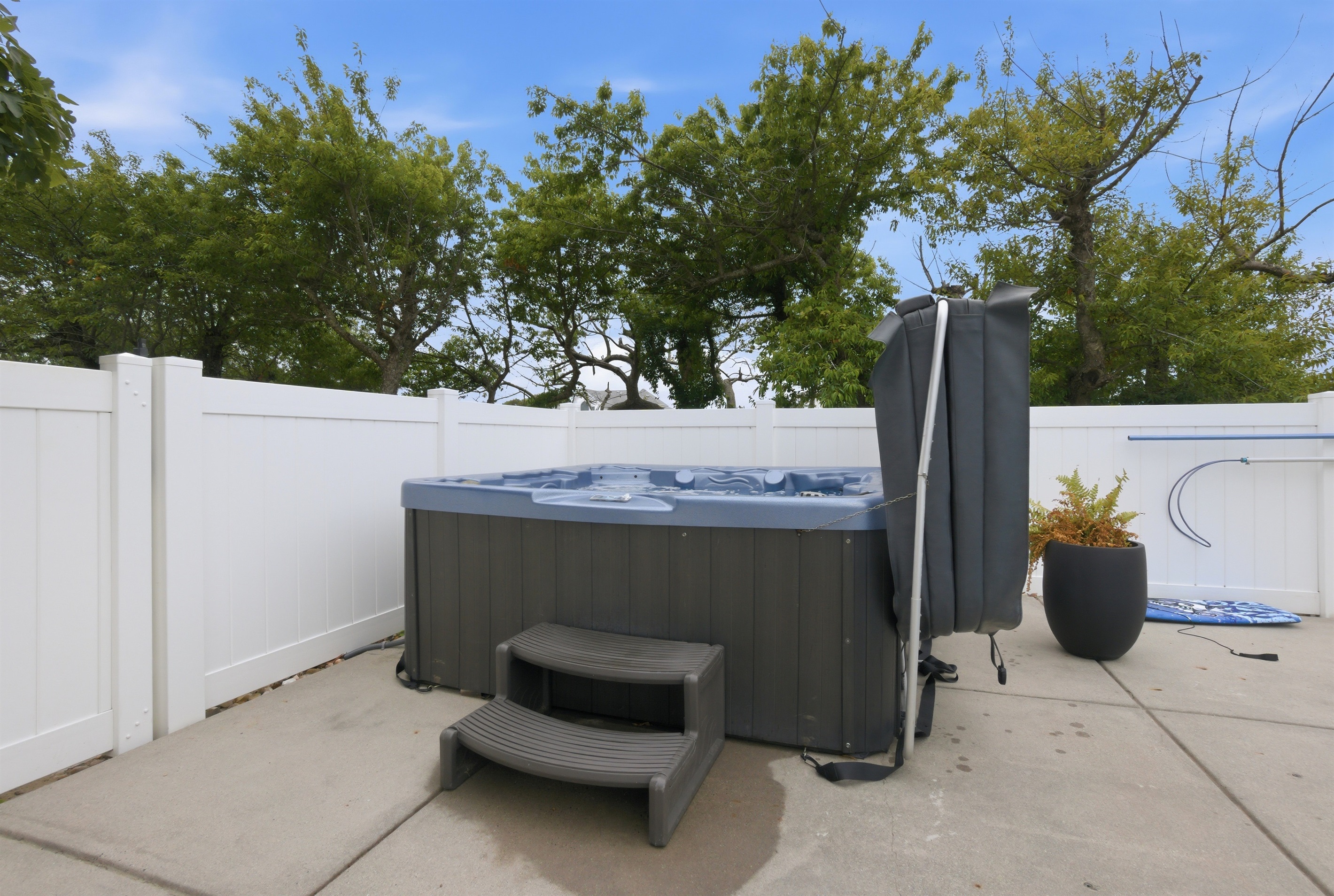 Outdoor hot tub area with privacy fencing and easy poolside access.