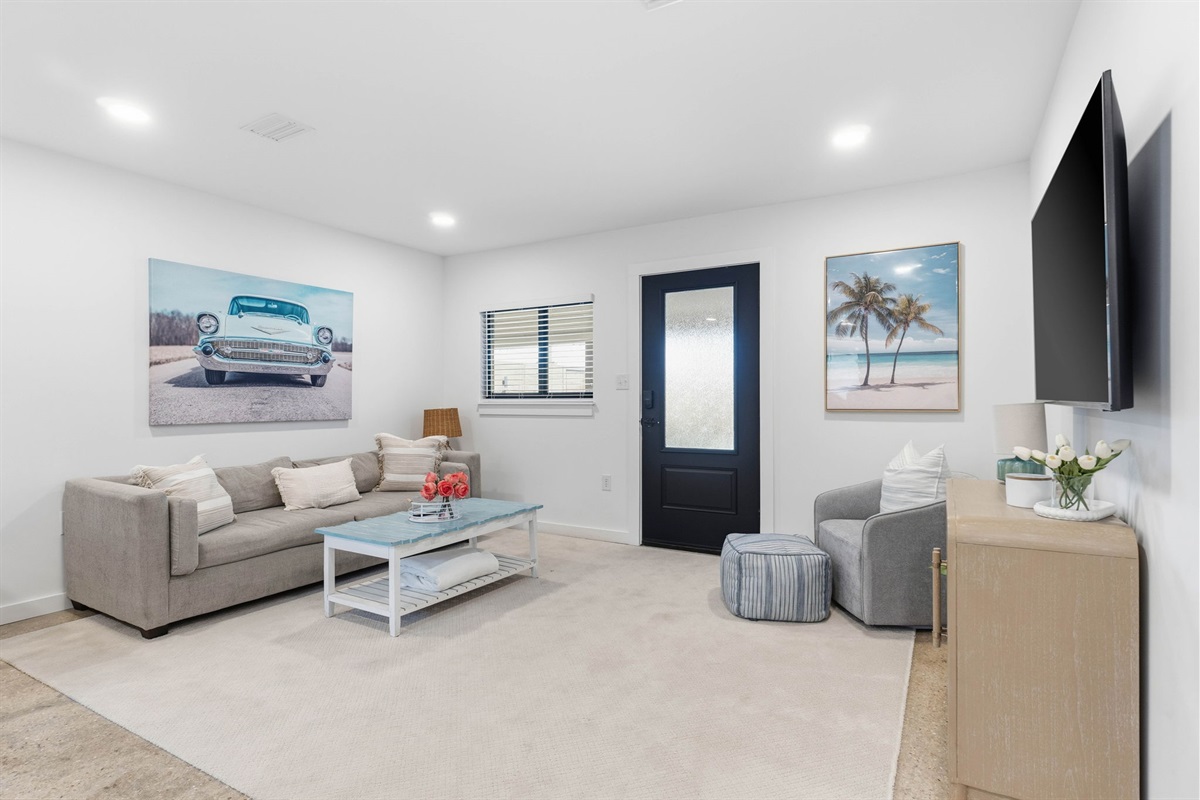 Living Area with comfortable furniture around a 55" Smart TV, dining space, access to covered patio