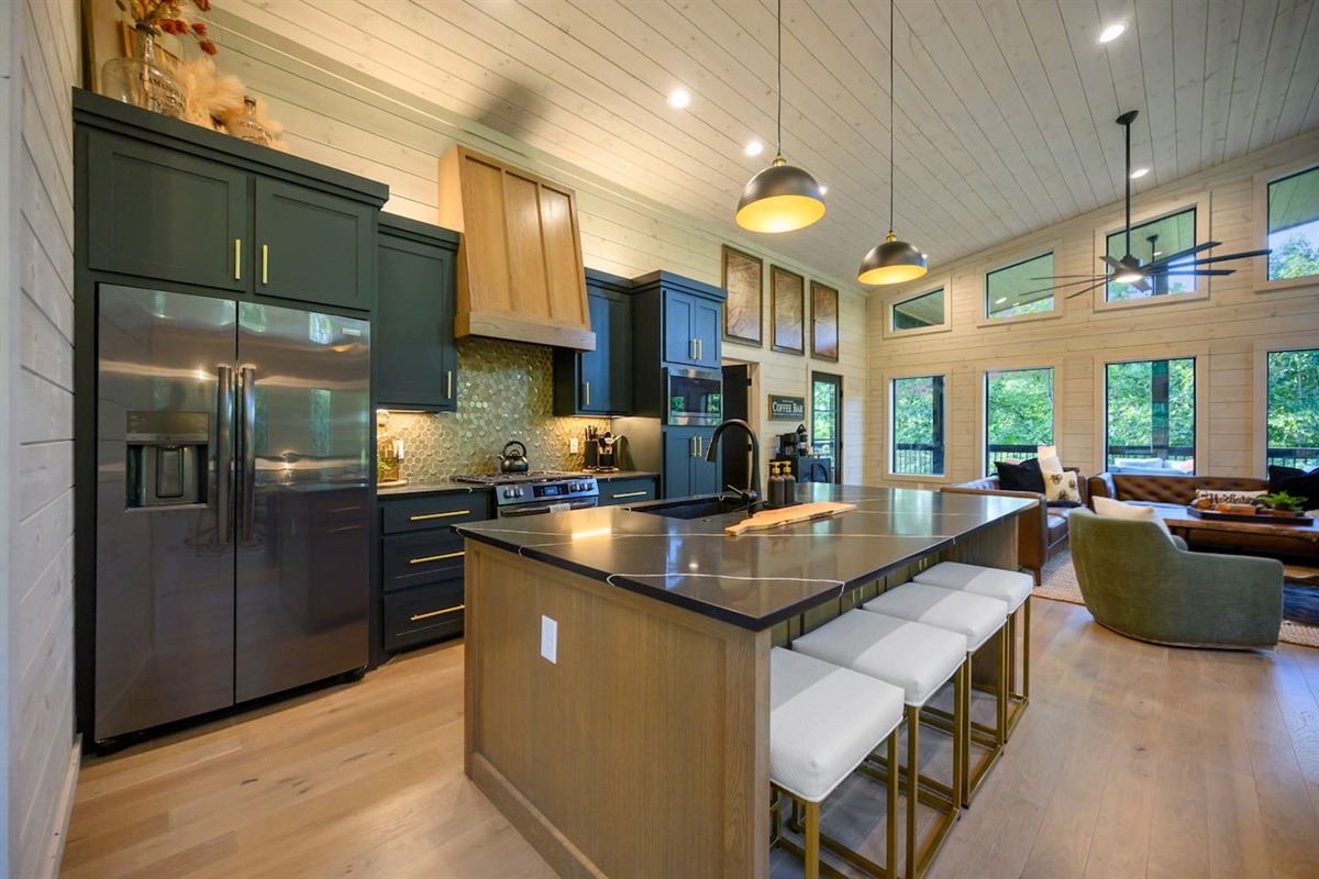 Kitchen features black stainless appliances, custom built cabinets with white oak island and matching vent hood.