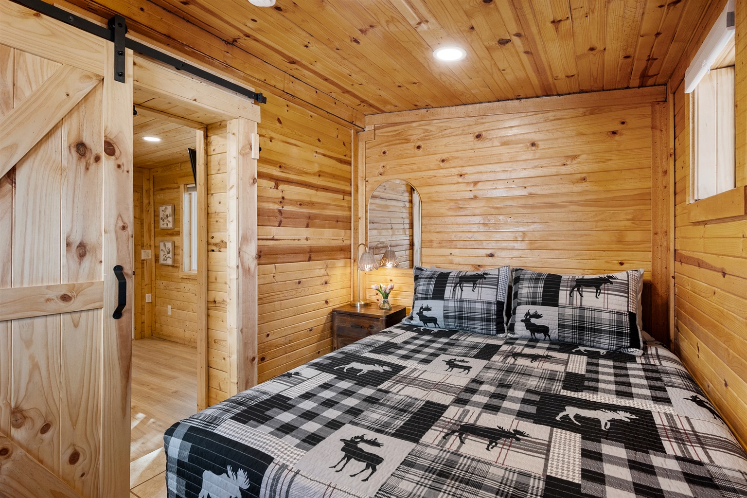 Step into this cozy little hideaway, just a step up from the living room and tucked behind a rustic barn door. With warm T&G walls, a comfy queen bed, blackout shades, and a private door to the backyard, it’s your dreamy escape!