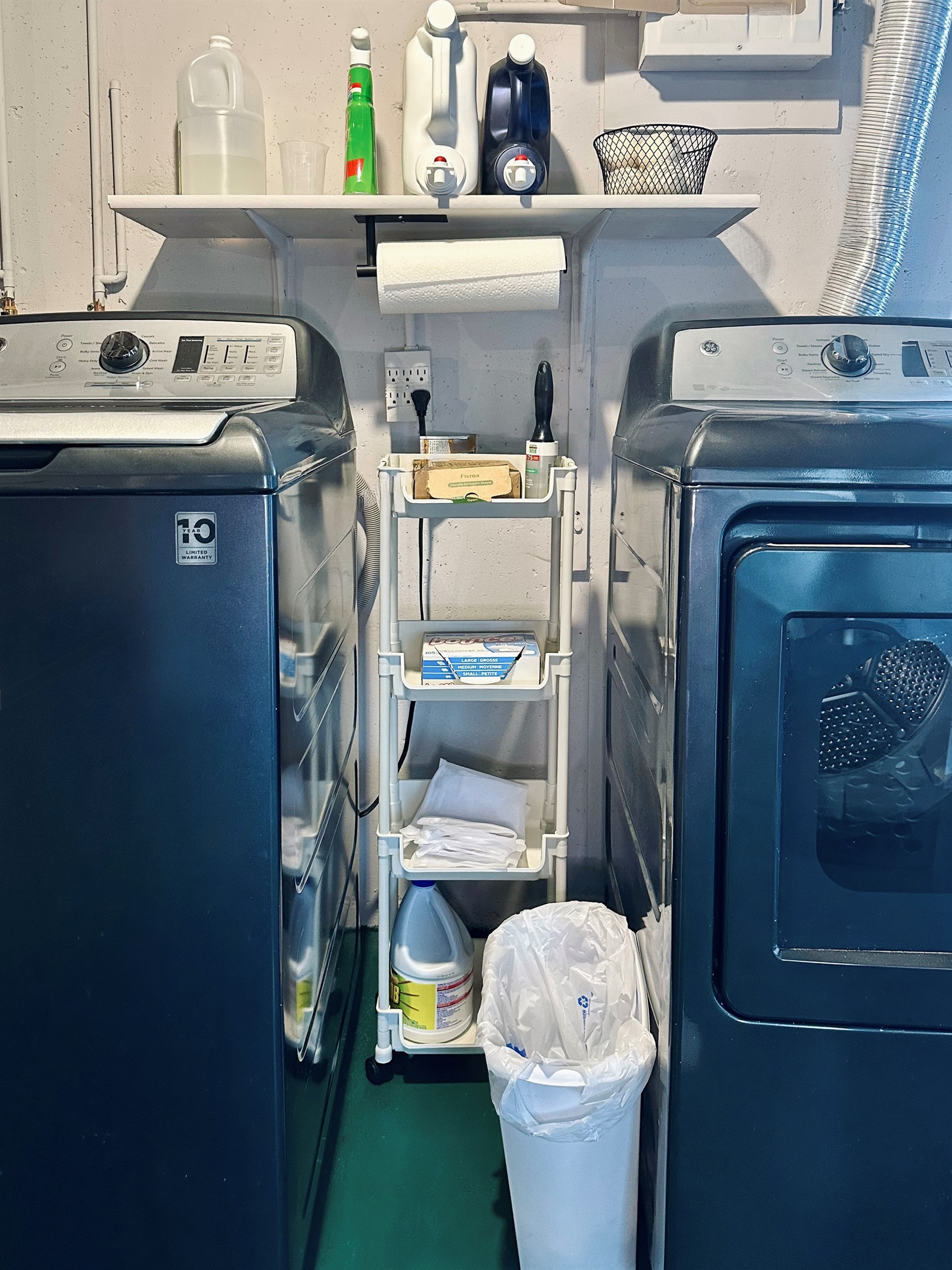 Fully equipped laundry area featuring a full-size washer and dryer, stocked with liquid detergent, detergent sheets, fabric softener, dryer balls, dryer sheets, stain remover, bleach, laundry bags, and a lint roller.