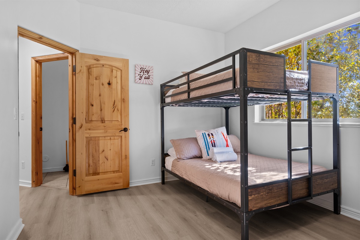 Bright lower-level bunk room with natural light and cozy bedding, ideal for families or group stays.