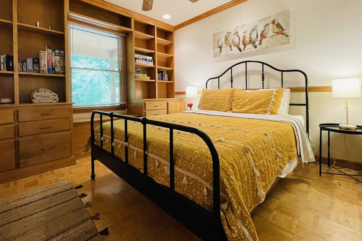 Cheery and comfortable main floor bedroom has a queen bed and a book nook with games and puzzles