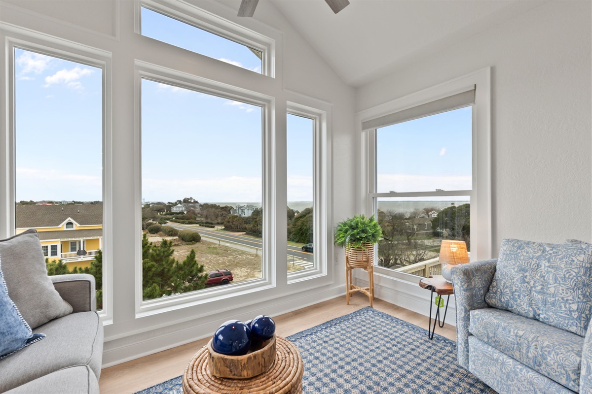 Another angle of the sitting space, highlighting the panoramic windows and relaxed seating.
