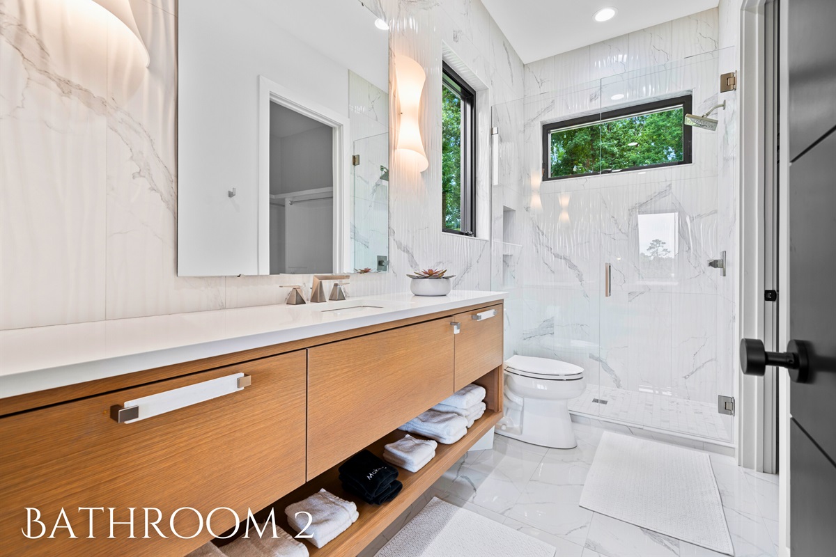 This elegant bathroom features a sleek vanity and a spacious shower, combining modern design with practical functionality.