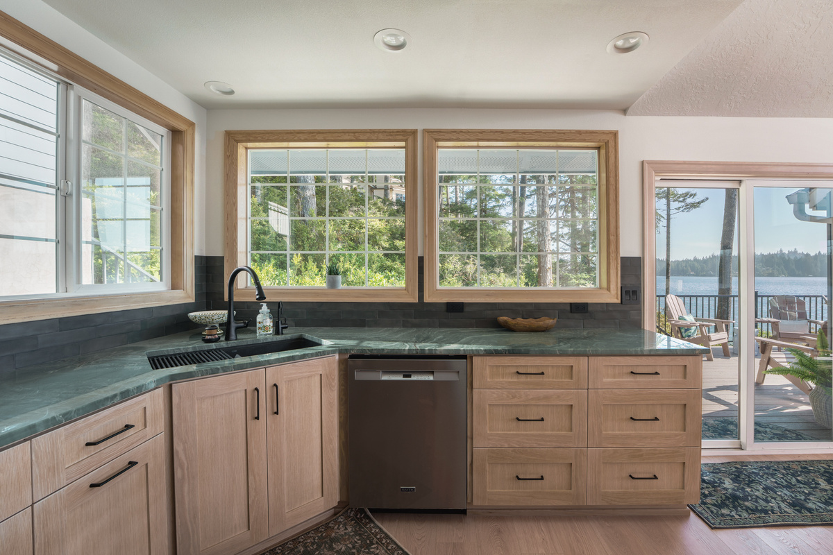 Fully equipped kitchen with modern appliances, generous counter space, and large windows that fill the room with natural light. Coffee station includes Keurig k-cup pods and traditional ground coffee maker