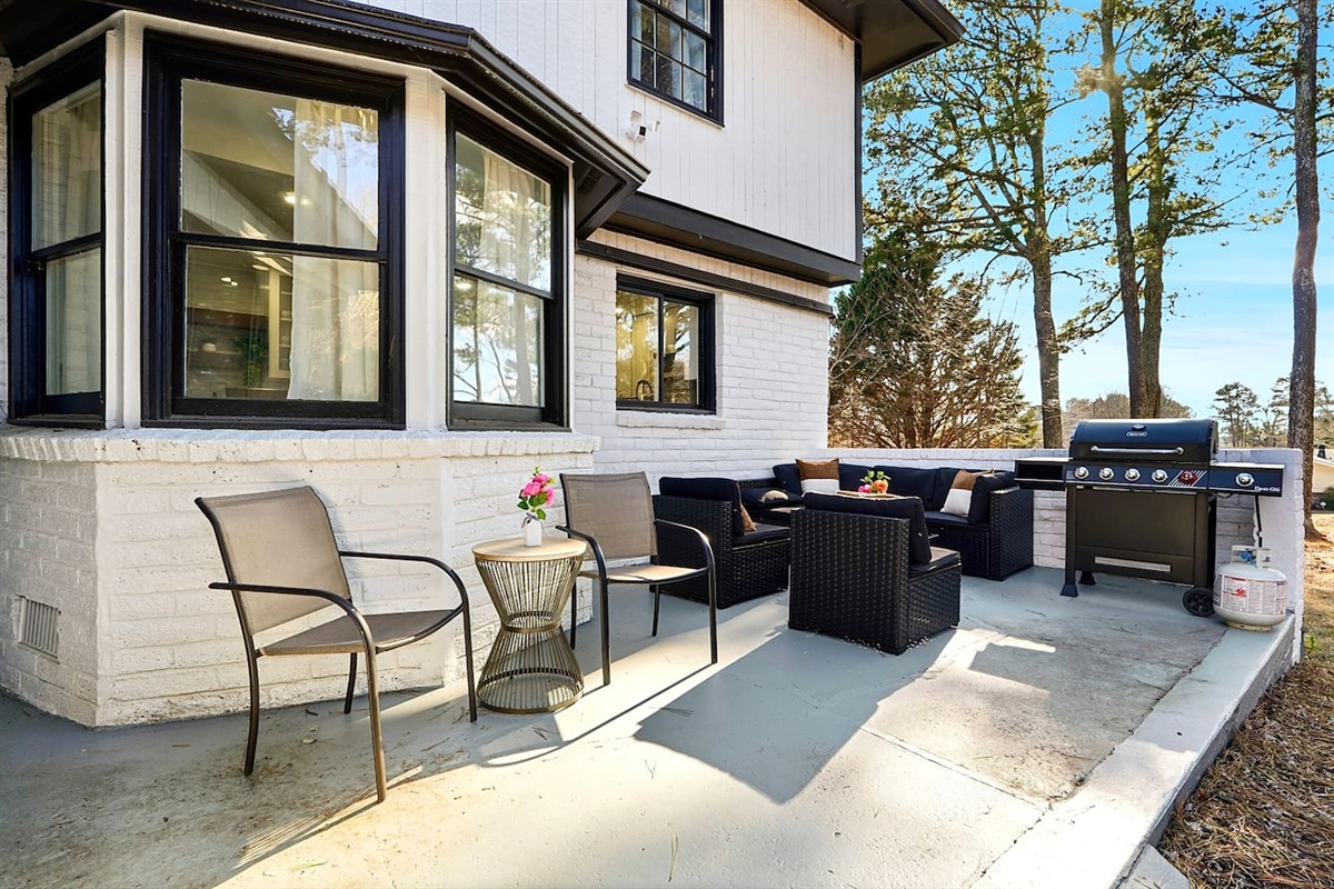 Inviting patio with black outdoor furniture, beige chairs, and a propane grill. A great space to relax, dine outside, or enjoy time with friends and family.