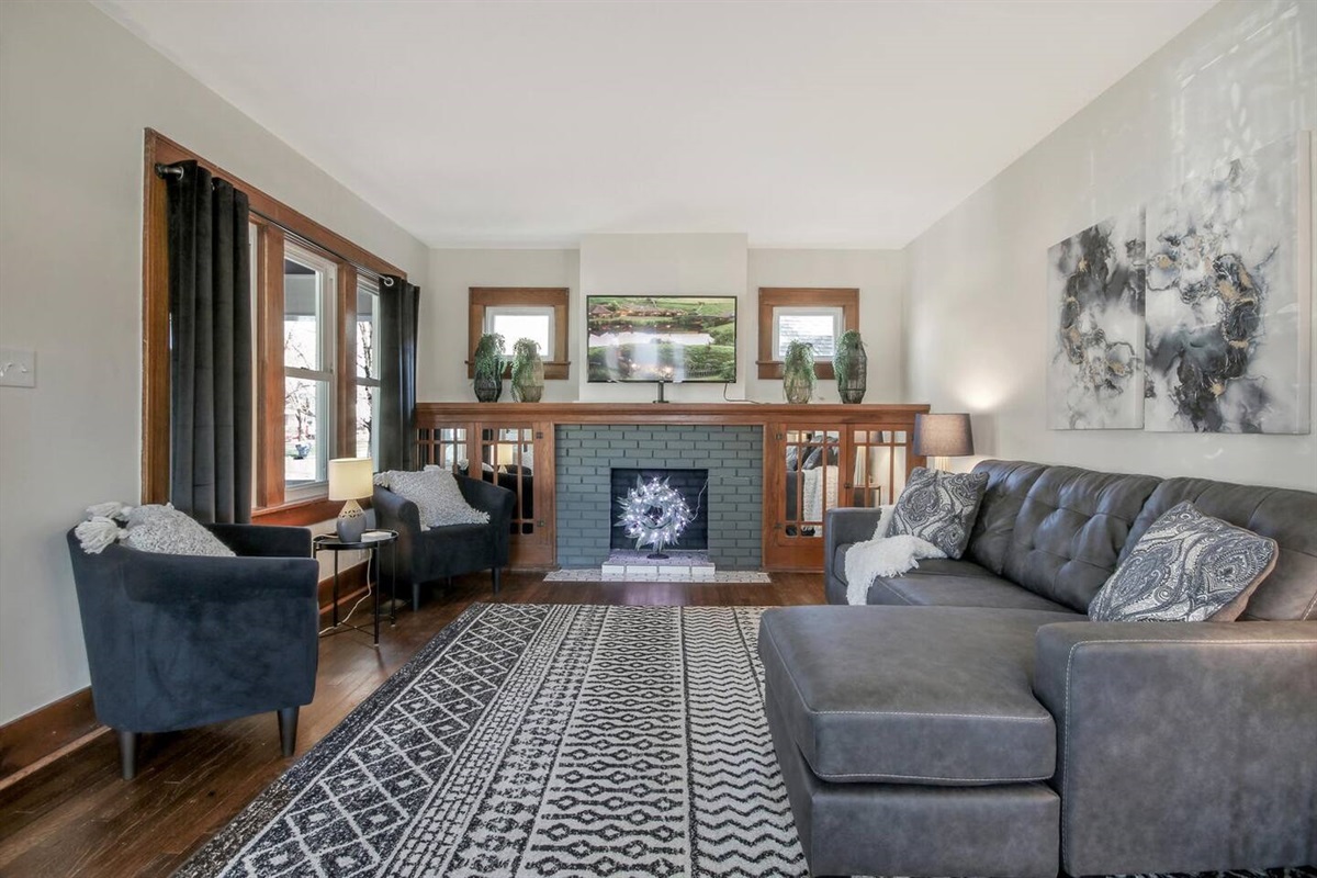 Front living room on the main floor features original wood trim, expansive seating, and a large flat screen smart TV.