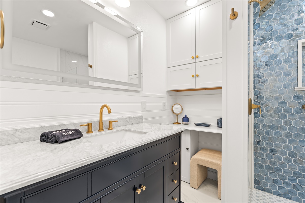 Spa-inspired bathroom featuring a marble vanity, brushed gold fixtures, and a stunning blue hex tile walk-in shower.