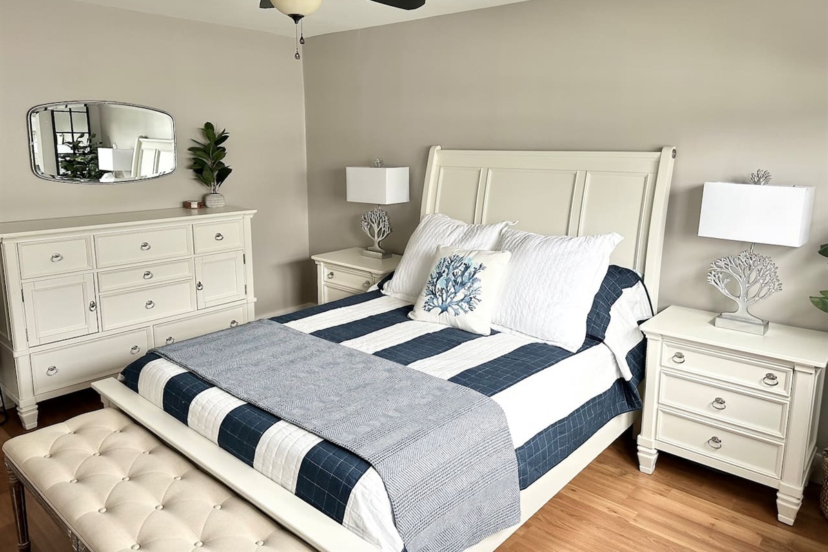 Unwind in this bright, coastal bedroom featuring a comfortable bed with crisp striped linens. This well-appointed space includes a stylish tufted bench and elegant white furniture, making it easy to enjoy a restful stay before heading to the beach.