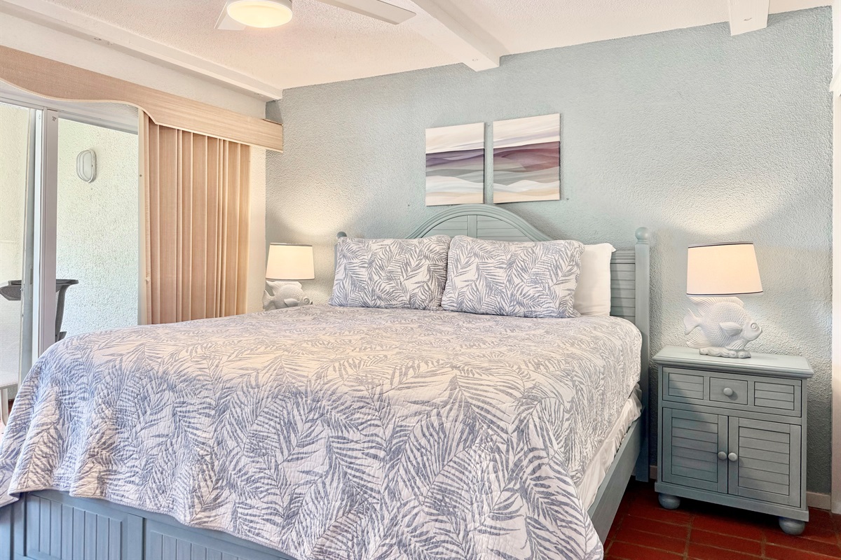 Primary bedroom with king bed, ceiling fan, ensuite bathroom  and balcony access
