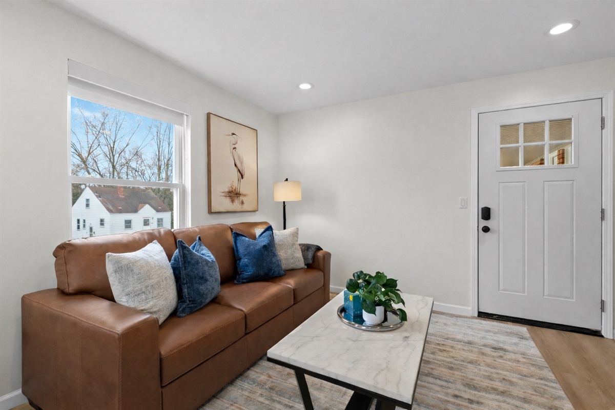 Warm, sunlit living room with plush leather sofa, modern décor, and smart TV—an inviting space to relax, unwind, and feel right at home.