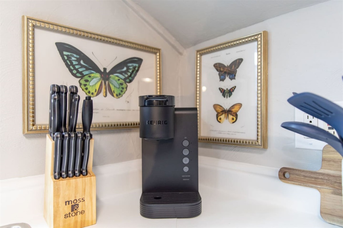 Start your mornings with a perfect cup of coffee from the Keurig, or enjoy a soothing tea from the provided assortment with the electric hot water kettle. The kitchen is fully stocked to meet all your culinary needs, and the delightful butterfly artw